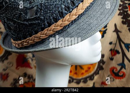 Blue summer paper straw hat on a white plastic mannequin head in a fashion store.  Female dummy wearing a woven blue fedora made of natural materials Stock Photo