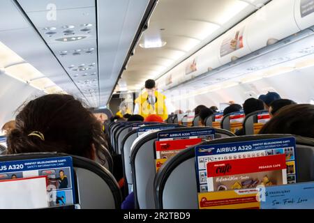 A flight attendant out of focus, blurred demonstrating life vest to passengers in a Boeing 737 operated by Pegasus airlines Stock Photo