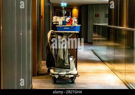 Housekeeping cart in a hotel corridor. Cleaning hospitality housekeeper's trolley beside a room entrance Stock Photo