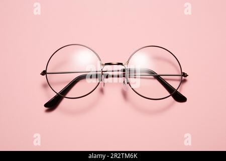 Glasses in round thin metal frame isolated on pink surface. Stock Photo