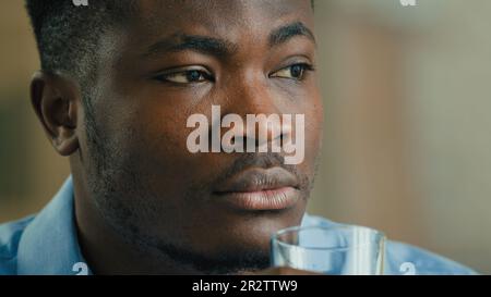 Close up African American ethnic man thoughtful businessman drink glass water take break drinking still liquid aqua balance thirst daily habit Stock Photo