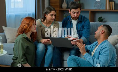 Multiracial friends working online with laptop order delivery at home diverse group men and women colleagues using computer web app in living room Stock Photo