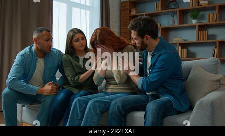 Upset woman cry desperate bullying at home multiethnic team friends support sad anxious girl on group psychological therapy colleagues women and men Stock Photo