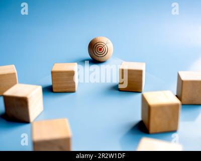 Wood sphere, leader with target icon in front of the wooden cube blocks on blue background. Concept of leadership, business target and success, motiva Stock Photo