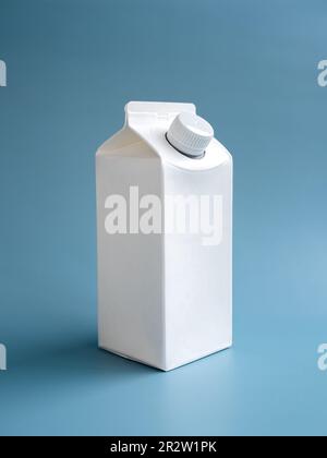 Mockup of a white milk or drinking water box, 1 liter with screw cap standing isolated on blue background, vertical style. Clean empty milk container Stock Photo