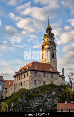 Golden illuminated building of tower and castle on rocky hill at sunset, Cesky Krumlov. Stock Photo
