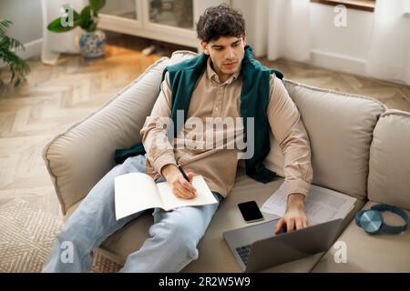Arabic guy having online class on laptop in living room Stock Photo
