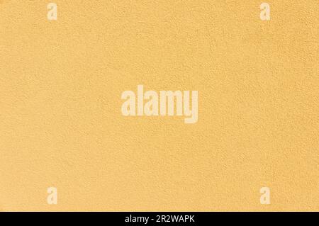 This close-up photo shows a wall covered in yellow decorative plaster. The bright shade of yellow gives the wall an energetic and cheerful feel. Stock Photo