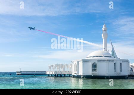 Jet with smoke trace over Alrahmah floating mosque with sea in foreground, Jeddah, Saudi Arabia Stock Photo