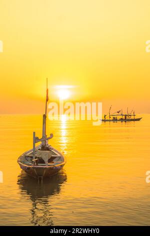 Moored boats during sunrise with yellow sky in Kenjeran, Surabaya, Indonesia. Long exposure photography. Stock Photo