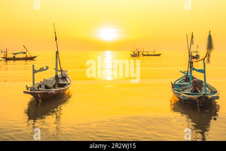 Moored boats during sunrise with yellow sky in Kenjeran, Surabaya, Indonesia. Long exposure photography. Stock Photo