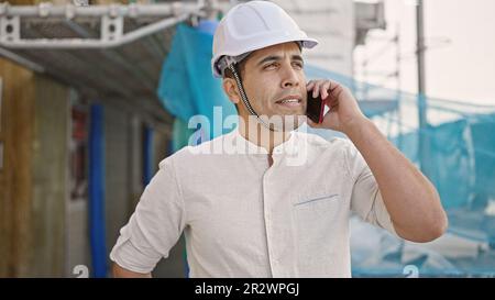 Young hispanic man architect talking on smartphone at street Stock Photo
