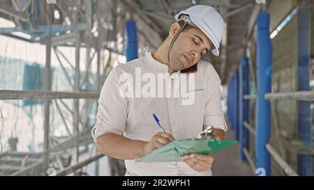 Young hispanic man architect talking on writing on document at street Stock Photo