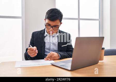 Down syndrome man business worker writing on document at office Stock Photo