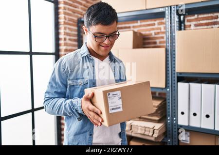 Down syndrome man ecommerce business worker holding package at office Stock Photo