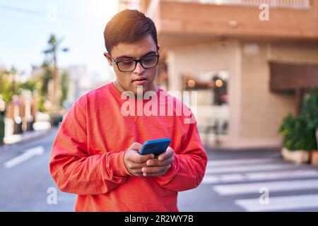 Down syndrome man using smartphone with serious expression at street Stock Photo