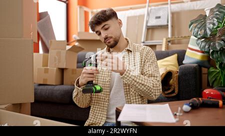 Young arab man repairing table using drill at new home Stock Photo