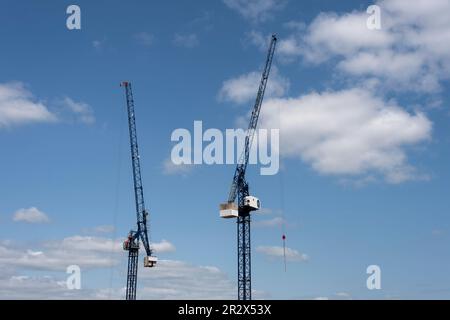 Two tower cranes against a blue sky Stock Photo
