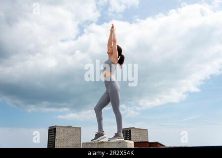 Fit, sporty woman doing an arm stretch outside, outdoor exercise, urban setting. Stock Photo