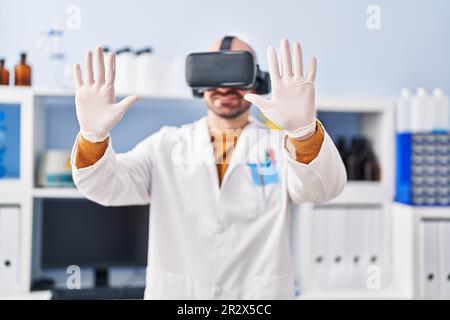 Young man scientist using virtual reality goggles at laboratory Stock Photo