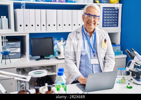 Senior man scientist using laptop working at laboratory Stock Photo