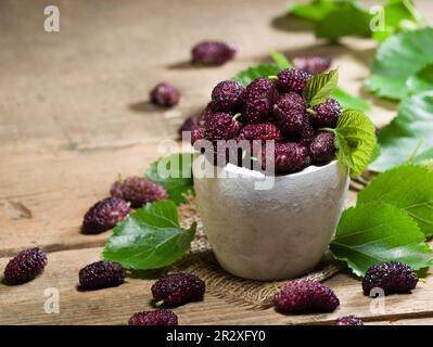 Fresh purple berries in rustic bowl. purple summer fruits Stock Photo