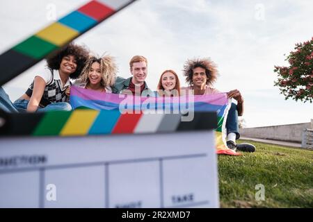 Group of friends sitting on the grass with lgtbi flag. Concept: pride, symbols, friendship Stock Photo