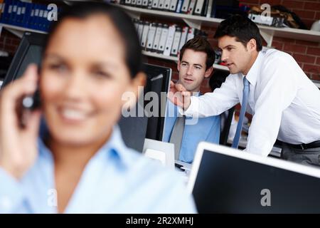 An office manager whos always there when needed. Two colleagues collaborating on a project together while a businesswoman takes a call in the Stock Photo