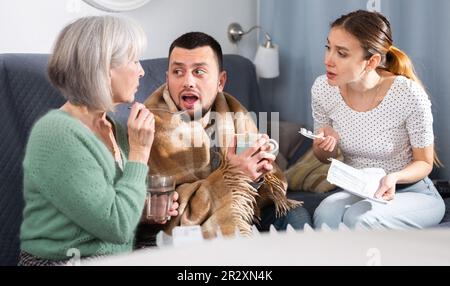 Mother giving medicines to sick adult son Stock Photo