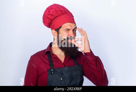 Professional chef in uniform shows sign ok. Winking bearded chef, baker gesturing excellent. Male cook in chef hat with perfect sign. Chef with taste Stock Photo