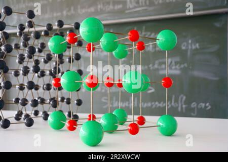 Atomic model in chemistry classroom with chalkboard in background Stock Photo