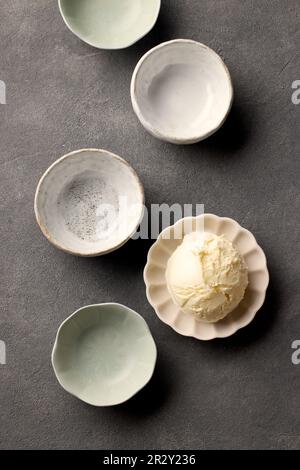 various empty and one full ice cream bowls on dark grey kitchen table, top view Stock Photo