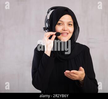 Portrait of woman in hijab helpline operator with headphones during work Stock Photo
