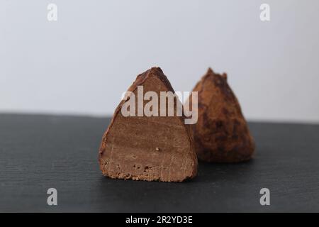 chocolate truffle candy pyramid cone triangle handmade on a gray black background with space for text copyspace. Chocolate Day. Sweet dessert, chocoho Stock Photo
