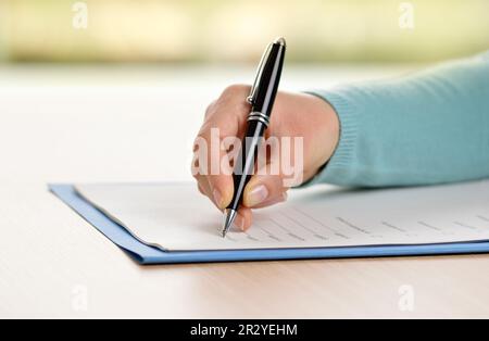 Close up of woman hand filling form on a table Stock Photo