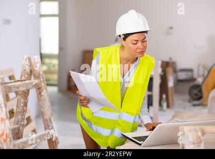 Focused female civil engineer using laptop at construction site Stock Photo