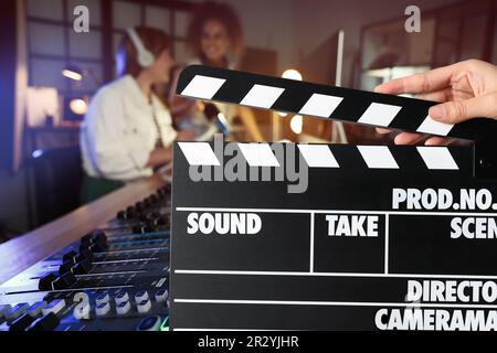 Shooting movie. Second assistant camera holding clapperboard in front of radio studio workers (actors) at film set Stock Photo