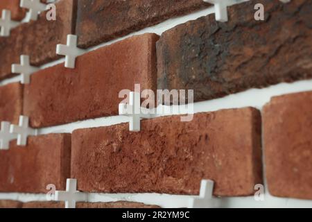 Decorative bricks with tile leveling system on wall, closeup Stock Photo