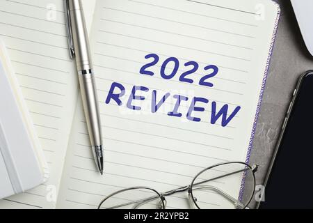 Text 2022 Review written in notebook, pen and glasses on grey table, top view Stock Photo