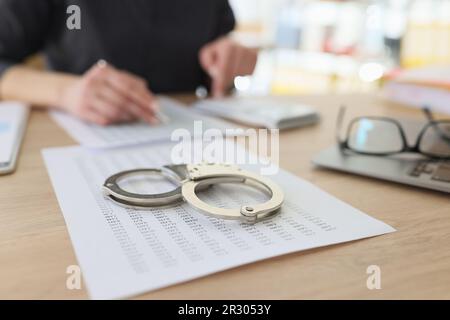 Handcuffs on investigation paper while worker making counts Stock Photo