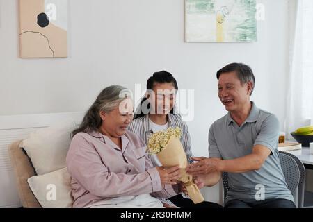 Husband and daughter visiting sick senior woman in hospital Stock Photo