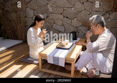 Happy mature Chinese couple drinking tea in tea room Stock Photo