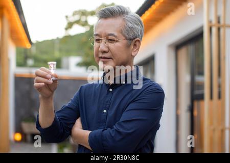Mature man drinking Chinese spirits Stock Photo - Alamy