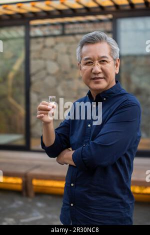 Mature man drinking Chinese spirits Stock Photo - Alamy