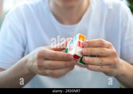 Young Caucasian girl holding and solving a Rubik's cube. Empty copy space for editor's text. Stock Photo