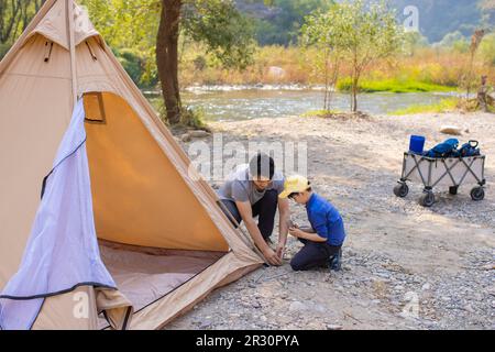 Little Chinese boy setting up camping tent together with his father Stock Photo