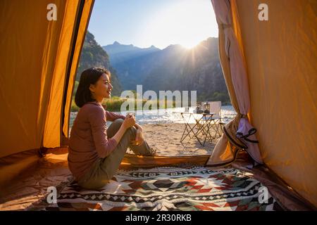 Cheerful young Chinese woman looking out from tent Stock Photo