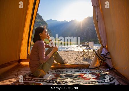 Cheerful young Chinese woman looking out from tent Stock Photo