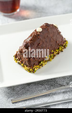 Dessert Cake from Malaga on stone table. Cake with banana inside, covered with chocolate sauce and hazelnuts Stock Photo