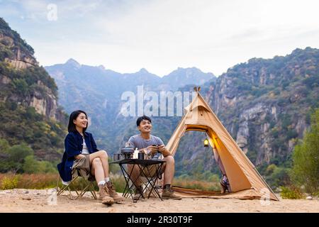 Happy young Chinese couple camping outdoors Stock Photo